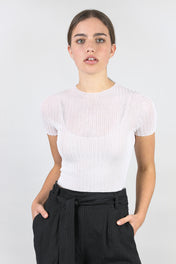 A woman standing wearing a white Standard Issue Cotton Tulle Crop Tee.